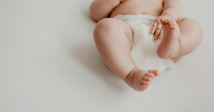 Pernas e pés de um bebé deitado confortavelmente, simbolizando bem-estar infantil.