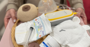 Bandeja com itens essenciais para a amamentação, incluindo fralda, seringa, bomba de extração de leite e mama de treino.
