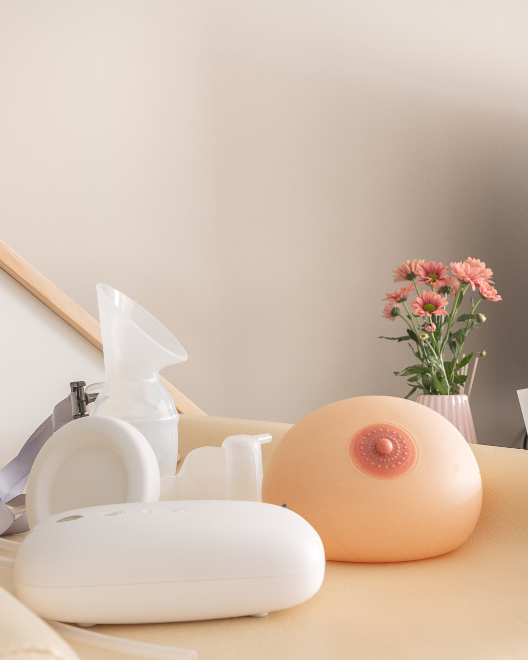 Apoio à Amamentação – Recursos e Acompanhamento Especializado na Romã Materiais utilizados no apoio à amamentação, incluindo bomba extratora e modelo de mama, sobre uma marquesa acolhedora