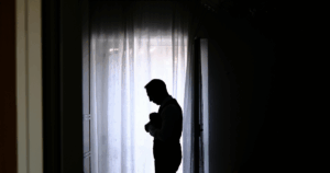 Pai ao colo do bebé junto a uma janela com luz suave, em ambiente acolhedor